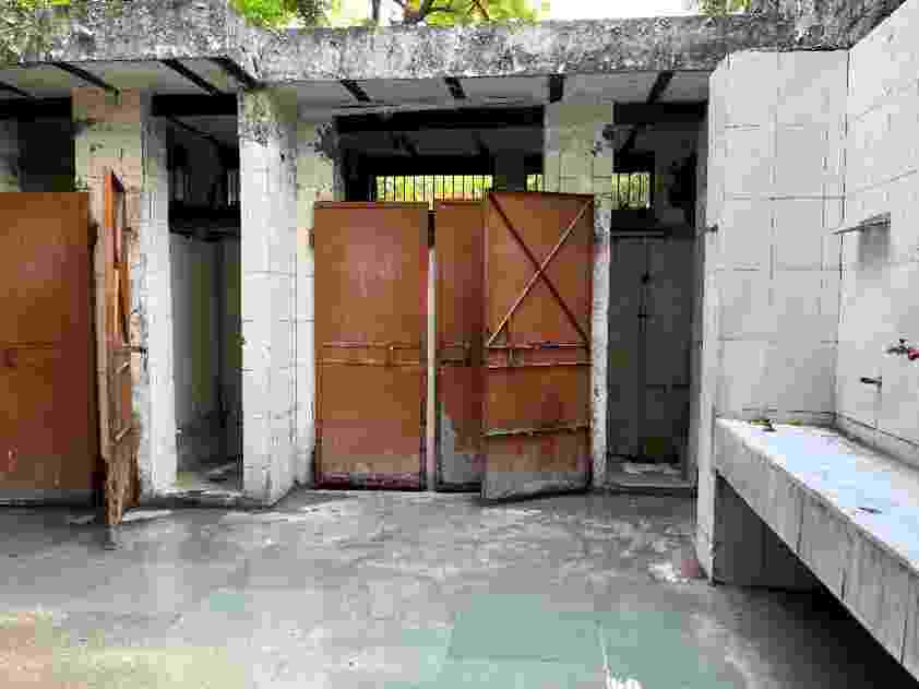 A poorly maintained community toilet building, with perished brickwork, broken taps, and other damaged infrastructure. 